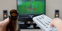 Man with a beer watching sport on TV